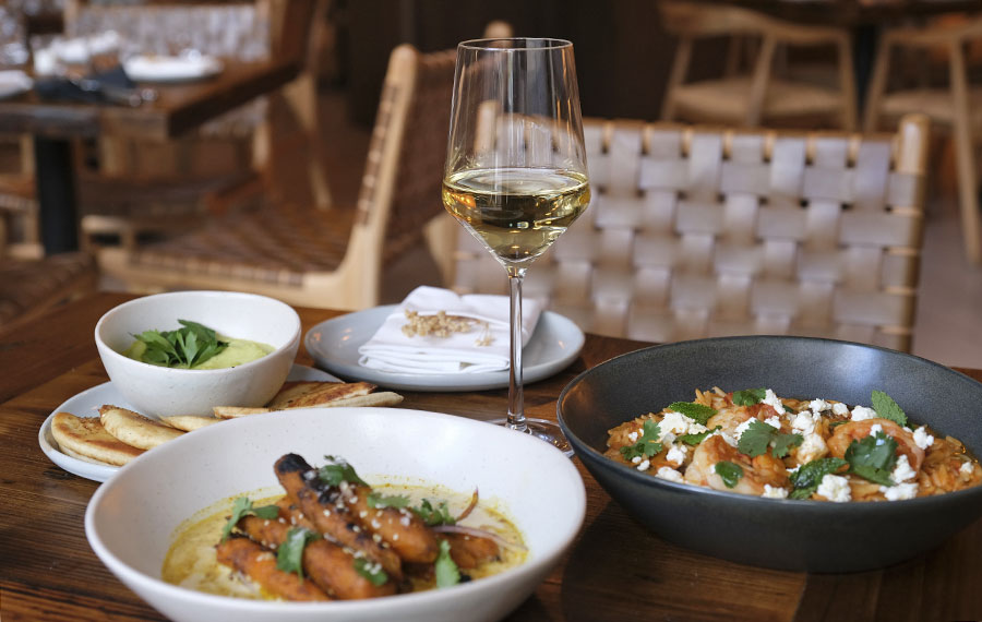 dinner entrees arranged on table with glass of white wine at eva oyster bar cocowalk miami