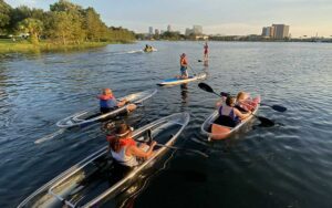 group of clear kayakers on lake with city skyline at epic paddle adventures orlando