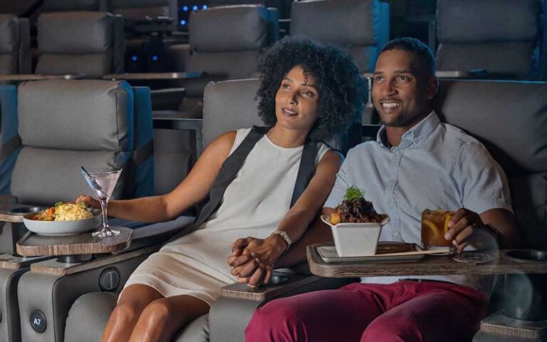 happy couple seated in luxury theater seats with entrees and wine watching movie at cmx cinebistro siesta key sarasota