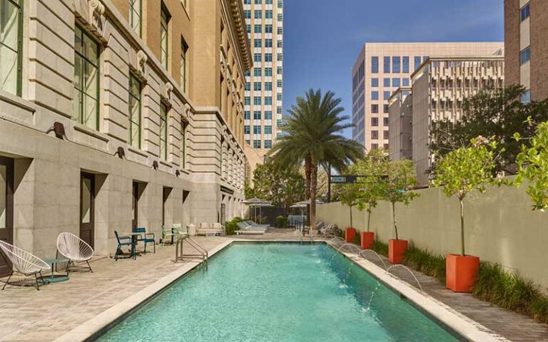 horizontal pool with fountains and seating between buildings at le meridien tampa