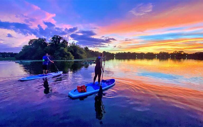 man and woman on standup paddleboards on lake with dazzling sunset sky at epic paddle adventures orlando
