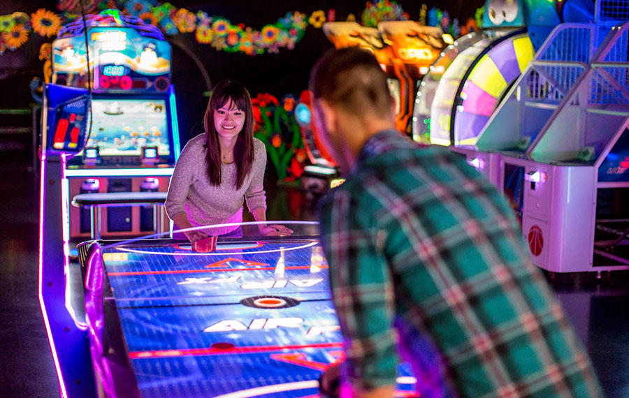 man and woman playing air hockey in colorful arcade at dezerland park orlando