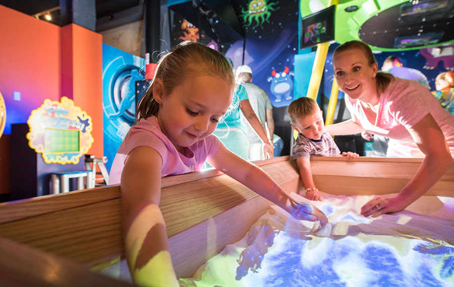 mom and kids interacting with sand box exhibit at wonderworks orlando