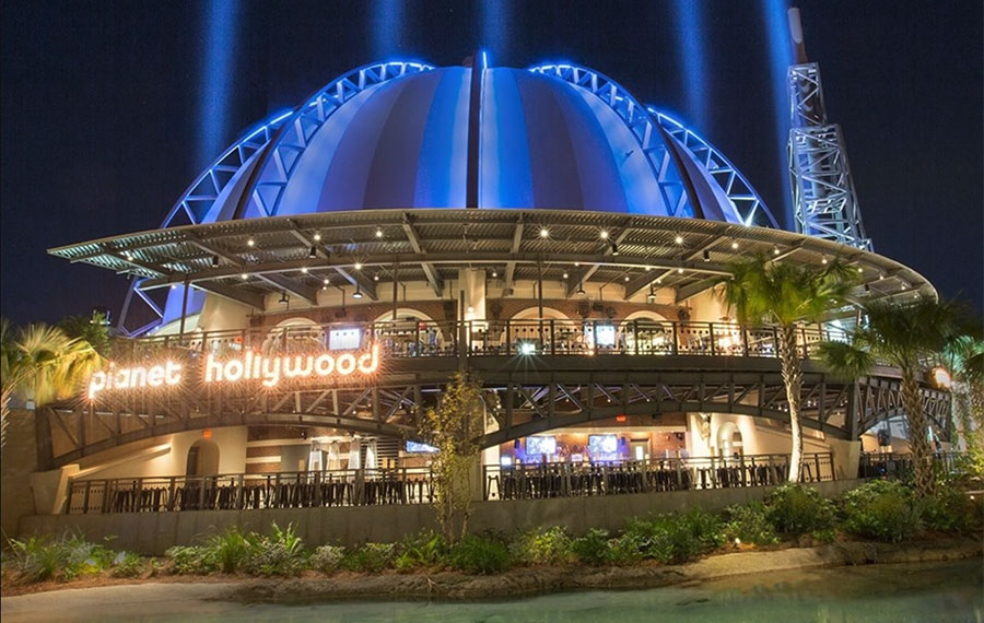 night exterior of dome shaped restaurant with patios and spotlights at planet hollywood disney springs