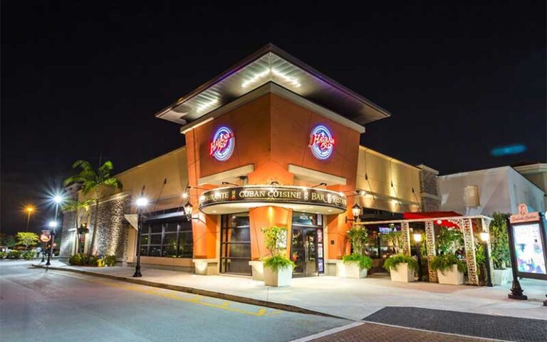 night exterior of restaurant with corner entrance and neon signs at havana 1957 cuban cuisine shops at pembroke pines