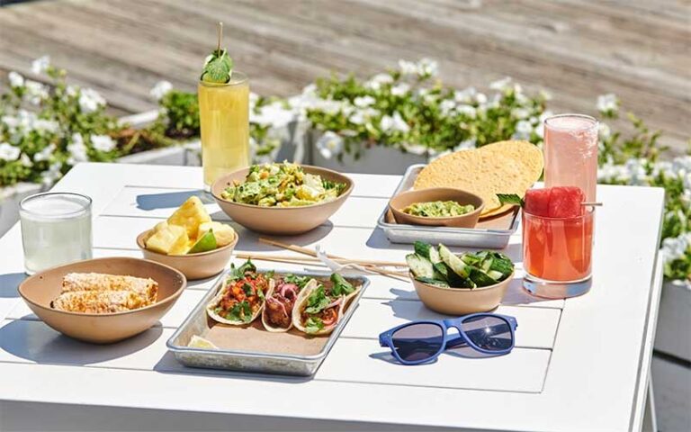 patio table in sunlight with several entrees and cocktails at bartaco tampa