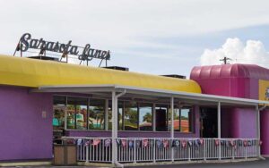 purple and yellow exterior building with sign and neon at sarasota lanes bowling