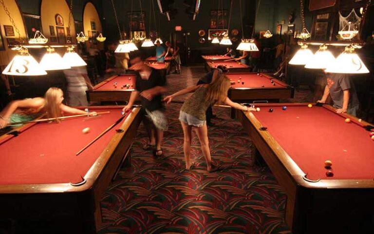rows of red felted pool tables with players at livingstones amusements sarasota