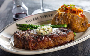 steak with butter asparagus and baked potato on white plate at village tavern shops pembroke gardens ft lauderdale