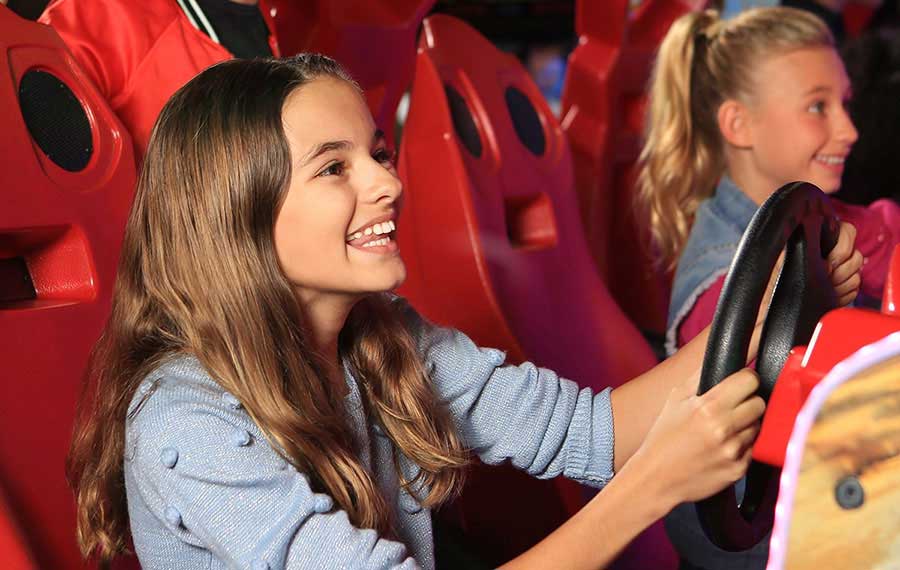 two girls smiling while playing racing arcade game dave busters fort myers