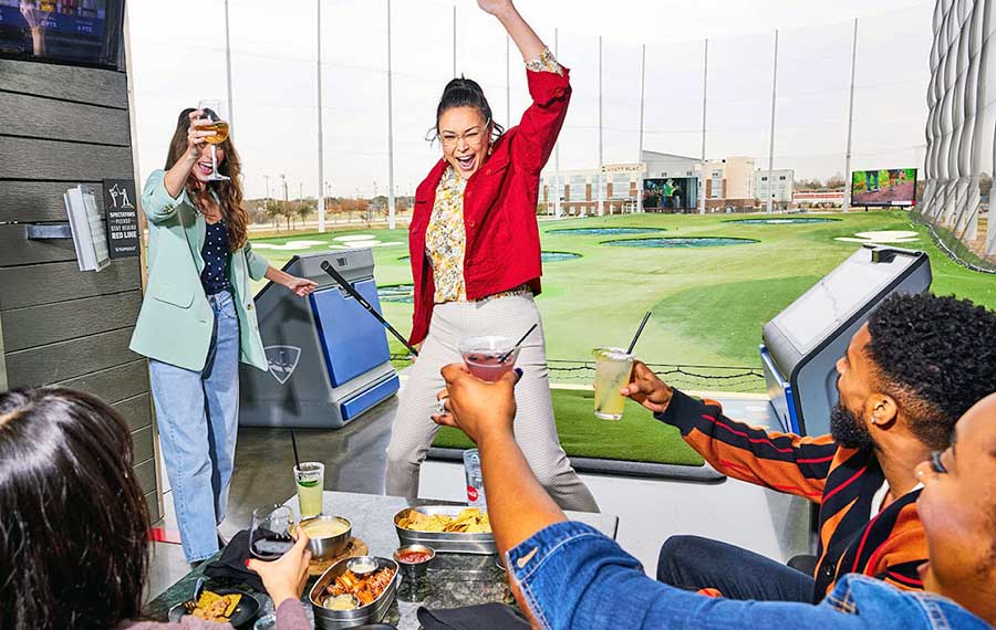 woman golfer celebrates with group of friends in bay topgolf fort myers