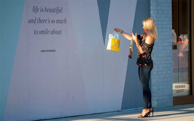young lady with shopping bag looking at mural next to kendra scott store at hyde park village tampa