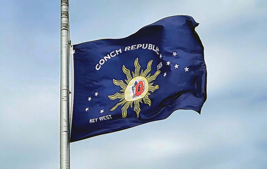 blue sky view of flagpole with conch republic flag key west