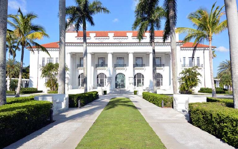 daytime exterior of white facade mansion with courtyard at henry morrison flagler museum palm beach