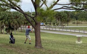 disc golfer with bag and disc at okeeheelee park west palm beach