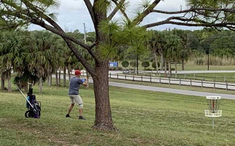 disc golfer with bag and disc at okeeheelee park west palm beach