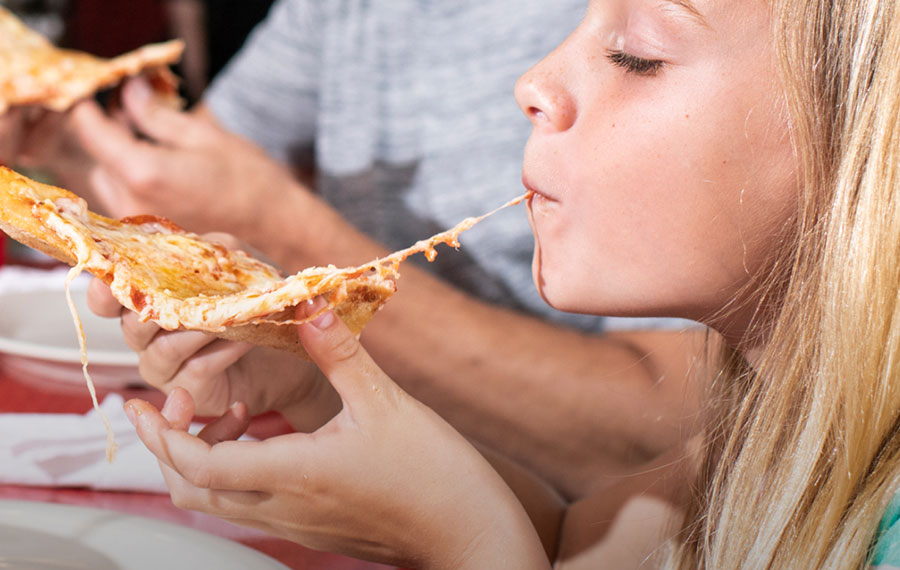 girl biting into pizza slice close up at flippers pizzeria tampa
