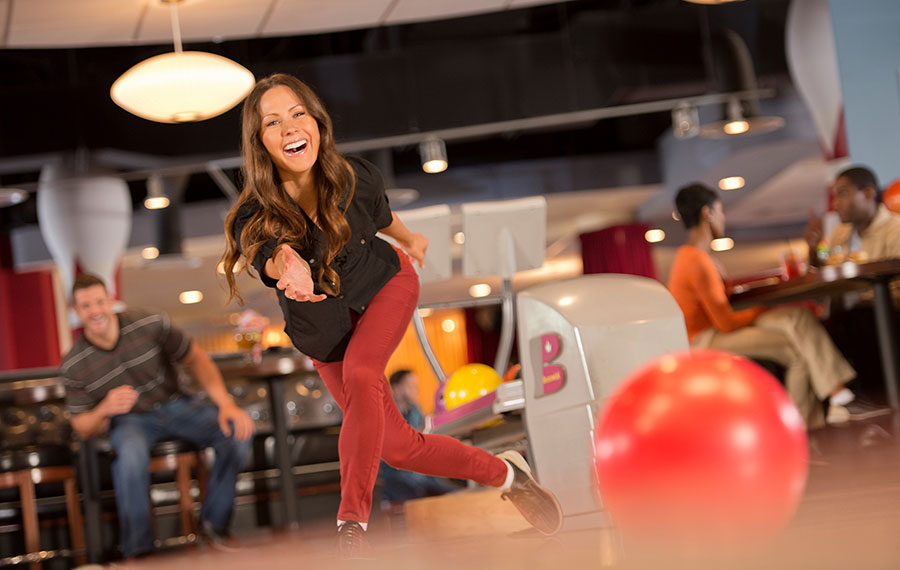 smiling woman bowling while man watches at splitsville tampa