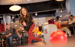 smiling woman bowling with man sitting at splitsville tampa