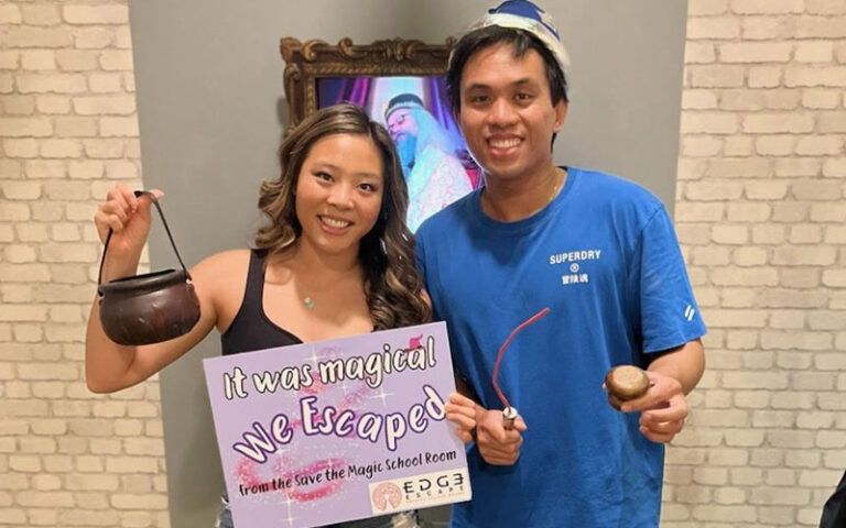 couple with sign and magic props at edge escape room kissimmee