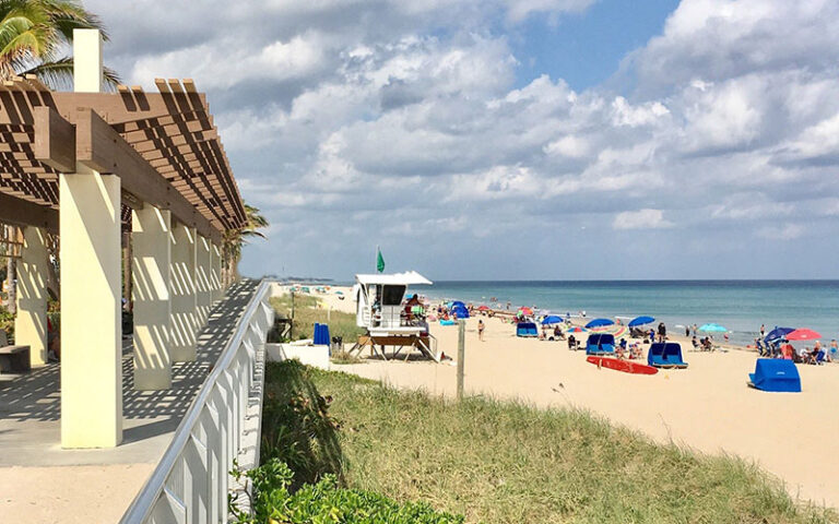 crowded beach with lifeguard hut and pavilion at r g kreusler park palm beach