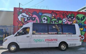daytime side shot of open top van with graffiti wall mural at open miami bus tours