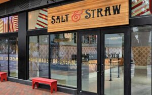 daytime store front with wood sign and dark windows at salt and straw cocowalk miami