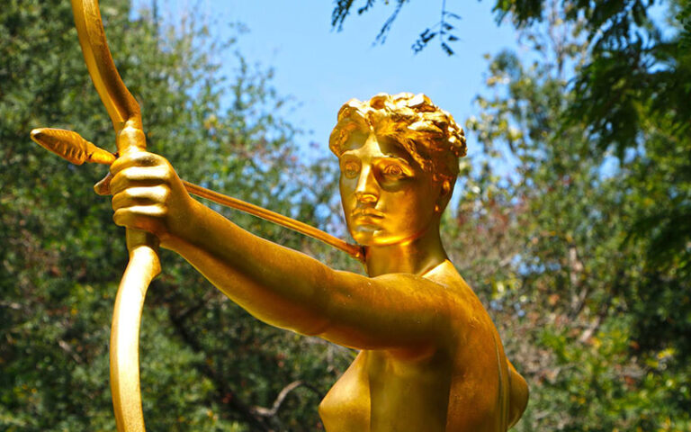 gold statue of archer in garden area at society of the four arts palm beach