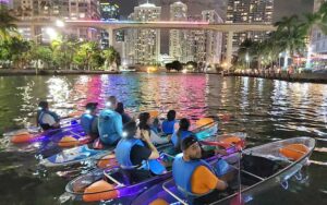 group of clear kayakers in bay at night with view of skyline at so flo water adventures miami