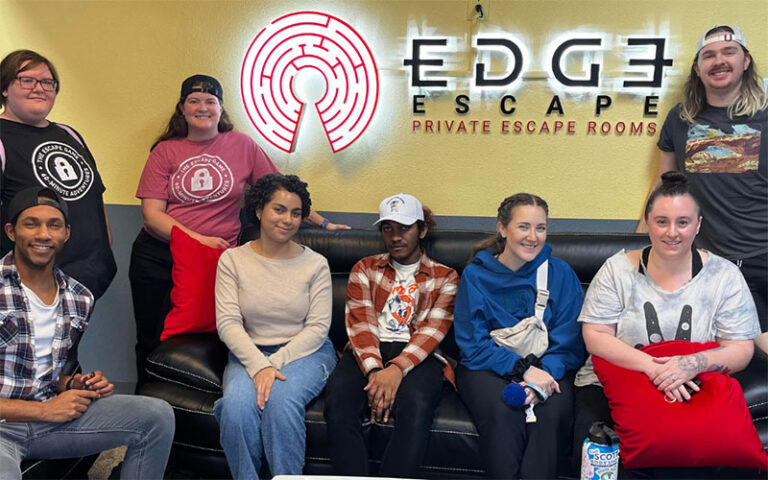 group of young participants on lounge couch with sign at edge escape room kissimmee