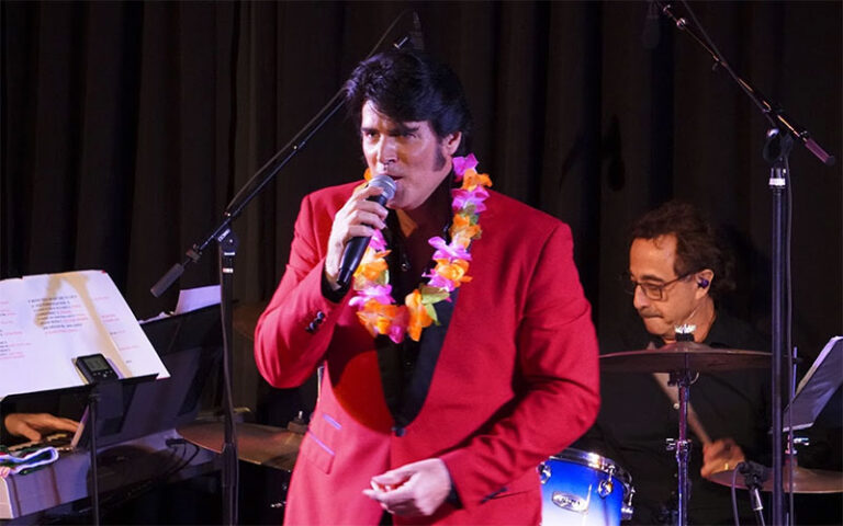 performer in red suit singing with band on stage at palm beach kennel club