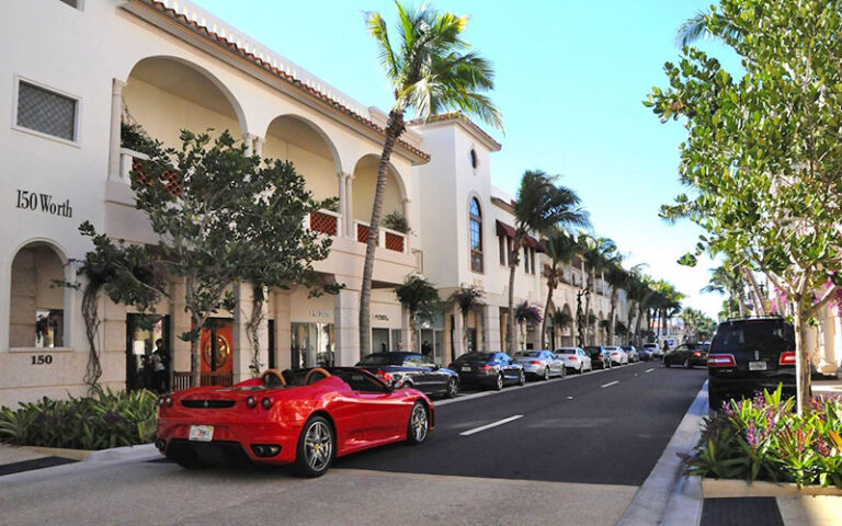 red sports car driving along shopping district street at worth avenue palm beach