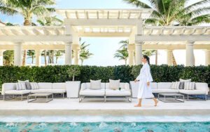 robed woman walking along poolside with seating at the spa at the breakers palm beach