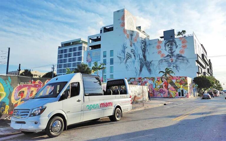 tour bus parked near building with huge murals at open miami bus tours