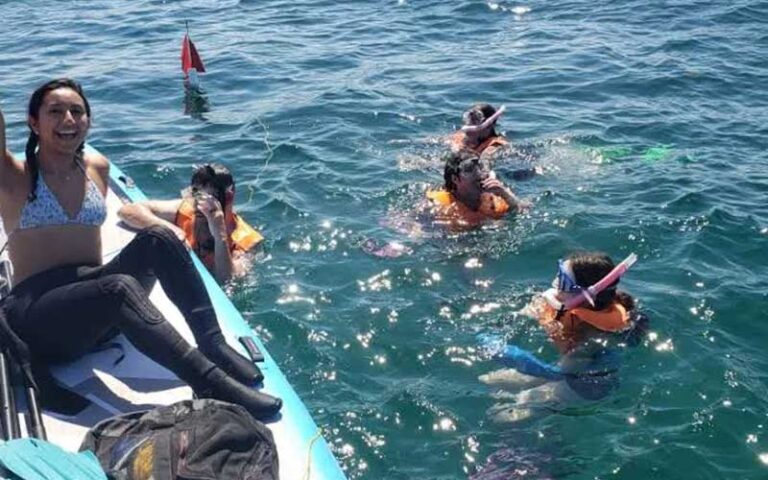 woman cheering on paddleboard next to snorkelers at so flo water adventures miami