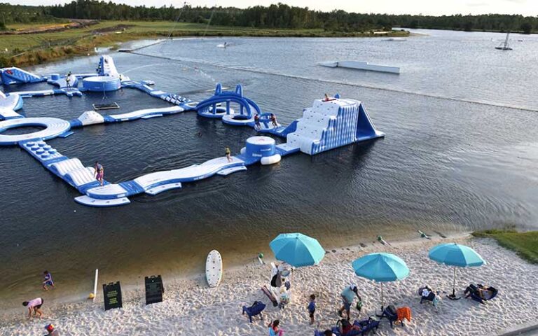 aerial view of aqua park inflatable course on lake with beach at nona adventure park orlando