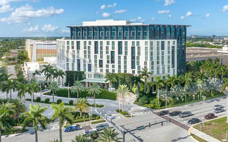 aerial view of high rise hotel with palm trees and blue sky with puffy clouds at hilton west palm beach