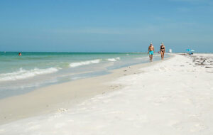 couple walking along beach with white sand and blue water at fort de soto park st pete
