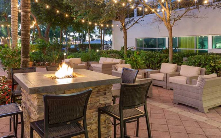 courtyard at night with fire pit chairs and palms at west palm beach marriott