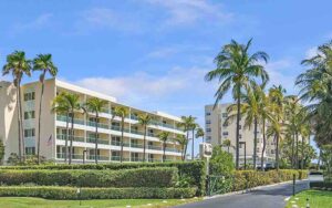 daytime exterior of hotel buildings with palm trees at the ambassador palm beach hotel residences