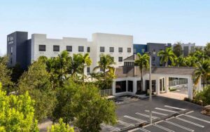 daytime front exterior of hotel with trees and entrance at hilton garden inn west palm beach airport