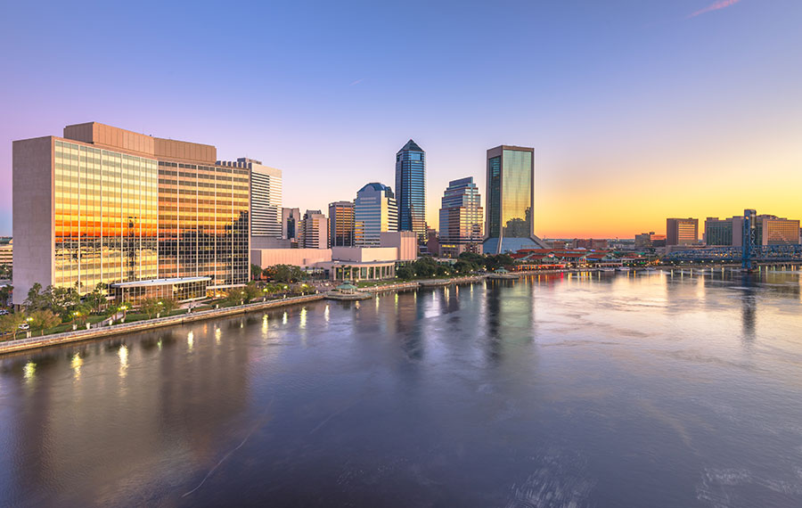 downtown city skyline across river with sunset orange glow reflected jacksonville