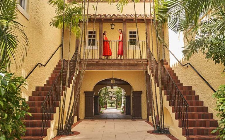 exterior archway with stairs and two women in red at the brazilian court hotel palm beach