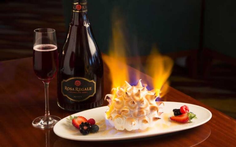 flambe dessert on oval plate with rose bottle and flute at hmf the breakers palm beach