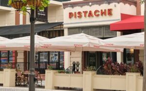 front exterior of restaurant with sign and patio seating at pistache french bistro west palm beach