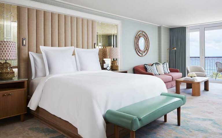 guest room with king size bed and balcony overlooking ocean at the four seasons palm beach
