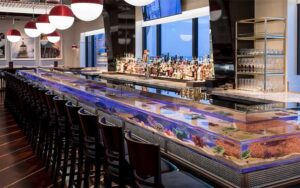 long bar with aquarium inside and globe lights at seafood bar the breakers palm beach
