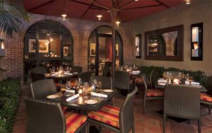 patio style dining area with warm red accents at the italian restaurant the breakers palm beach