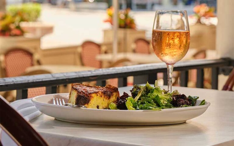 quiche with salad and wine on outdoor table at pistache french bistro west palm beach