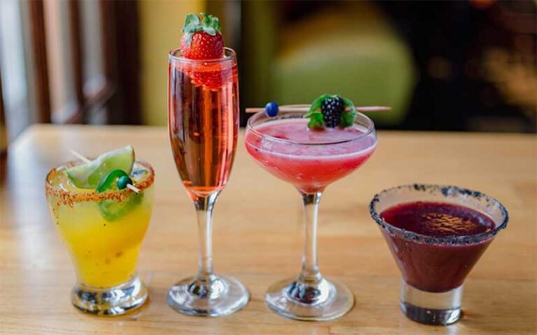 row of colorful cocktail drinks in different shaped glasses at cafe tu tu tango orlando